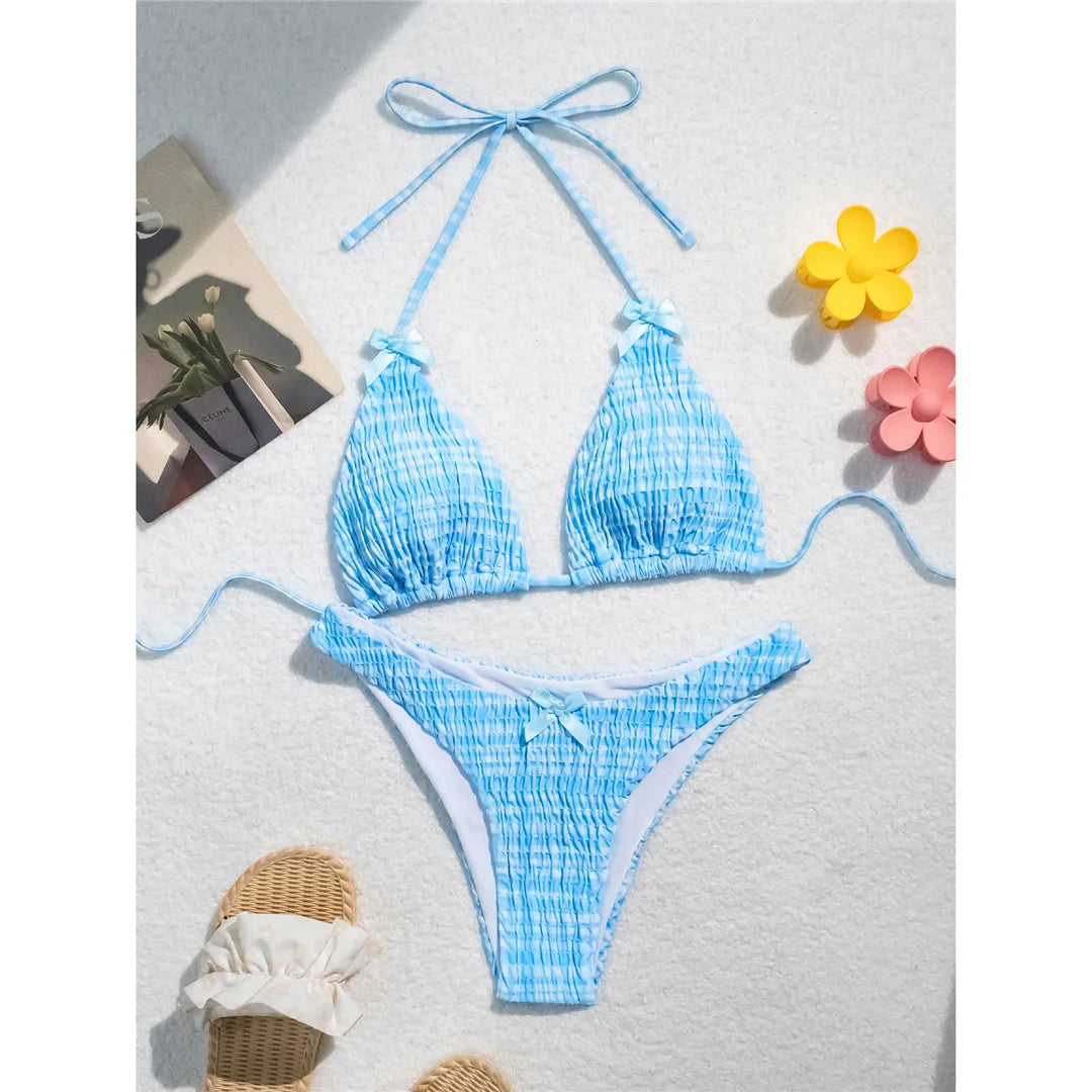 An elegant two-piece swimwear featuring a refined plaid pattern, soft wrinkled texture, and delicate bow detail, designed for a feminine and effortlessly chic beach look