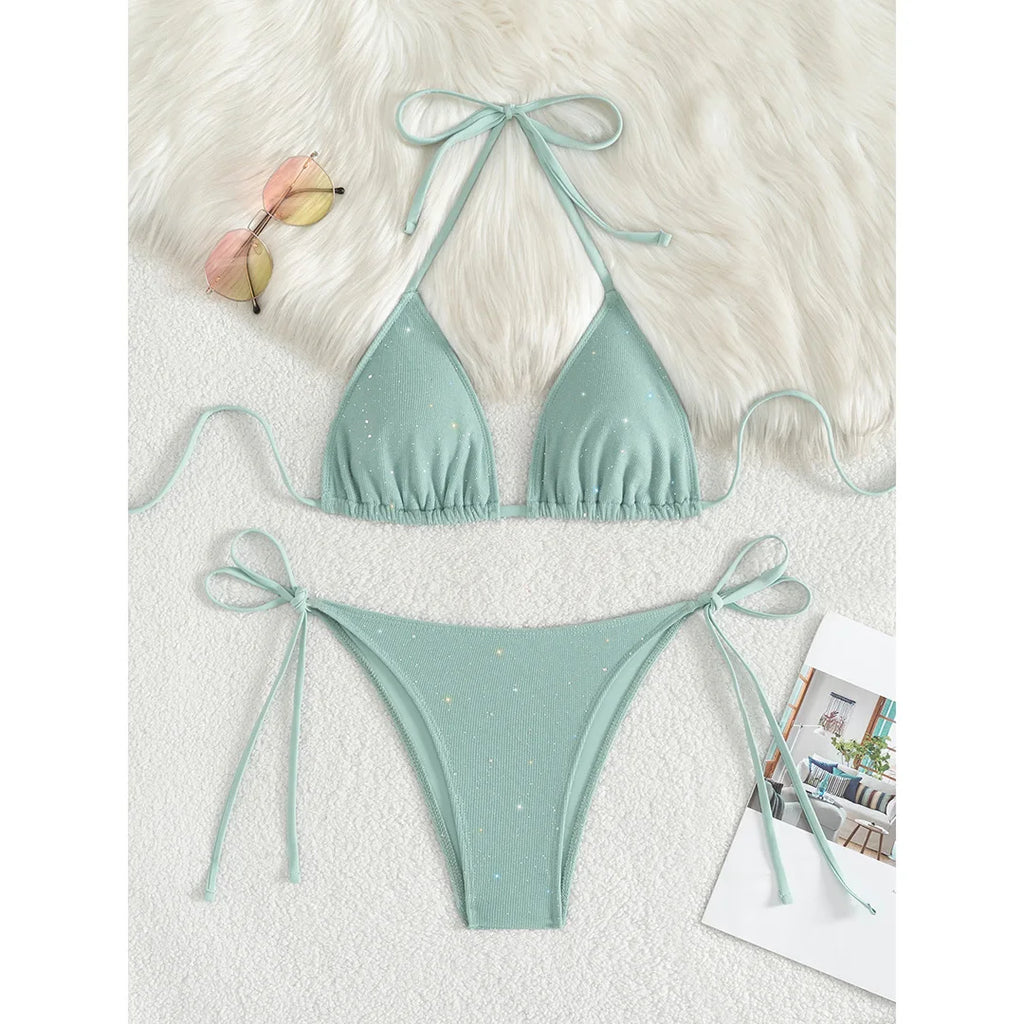 An elegant two-piece swimwear featuring a sparkling glitter finish, halter neckline, and high-leg cut, designed for a radiant and confident feminine beach look