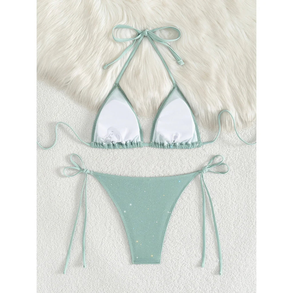 An elegant two-piece swimwear featuring a sparkling glitter finish, halter neckline, and high-leg cut, designed for a radiant and confident feminine beach look