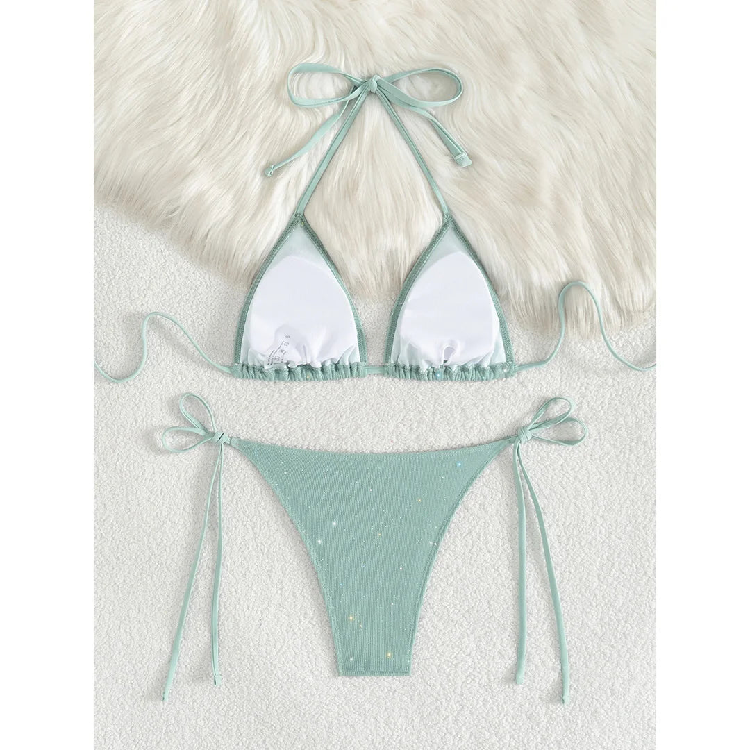 An elegant two-piece swimwear featuring a sparkling glitter finish, halter neckline, and high-leg cut, designed for a radiant and confident feminine beach look