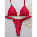 An elegant two-piece swimwear featuring a halter neckline with refined metal ring accents and a mini thong cut, designed for a bold, feminine, and confident beach look
