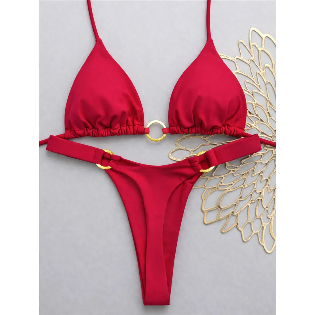 An elegant two-piece swimwear featuring a halter neckline with refined metal ring accents and a mini thong cut, designed for a bold, feminine, and confident beach look