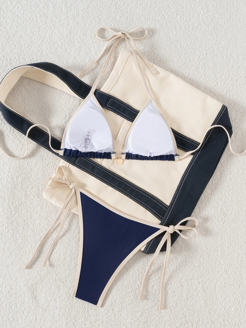 A modern two-piece swimsuit featuring elegant color-block detailing, tie-side accents, and a cross-back design, created for a confident and feminine beach look