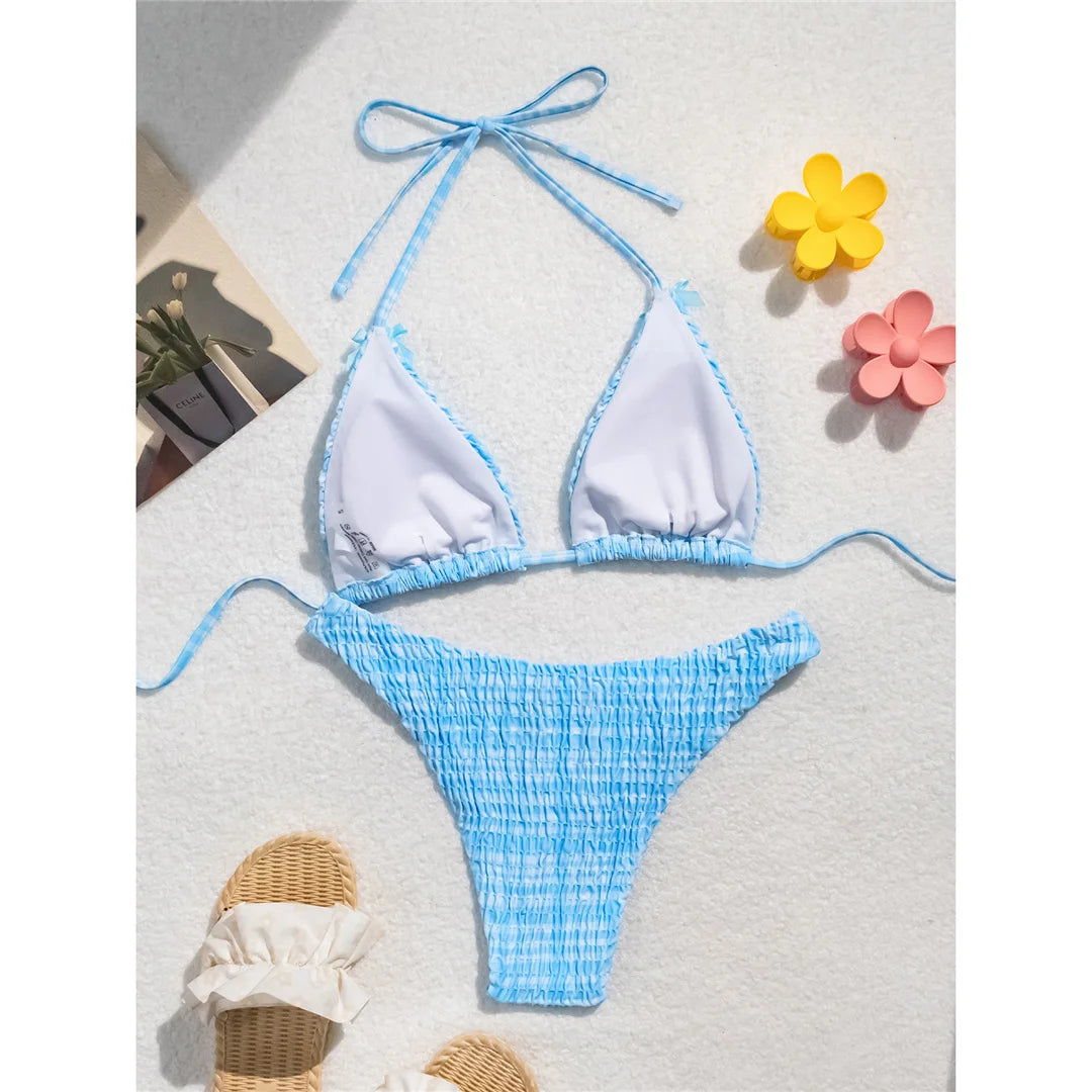 An elegant two-piece swimwear featuring a refined plaid pattern, soft wrinkled texture, and delicate bow detail, designed for a feminine and effortlessly chic beach look