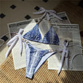 An elegant halter two-piece swimwear with a refined snakeskin-inspired print and strappy detailing, designed for a bold yet feminine beach look