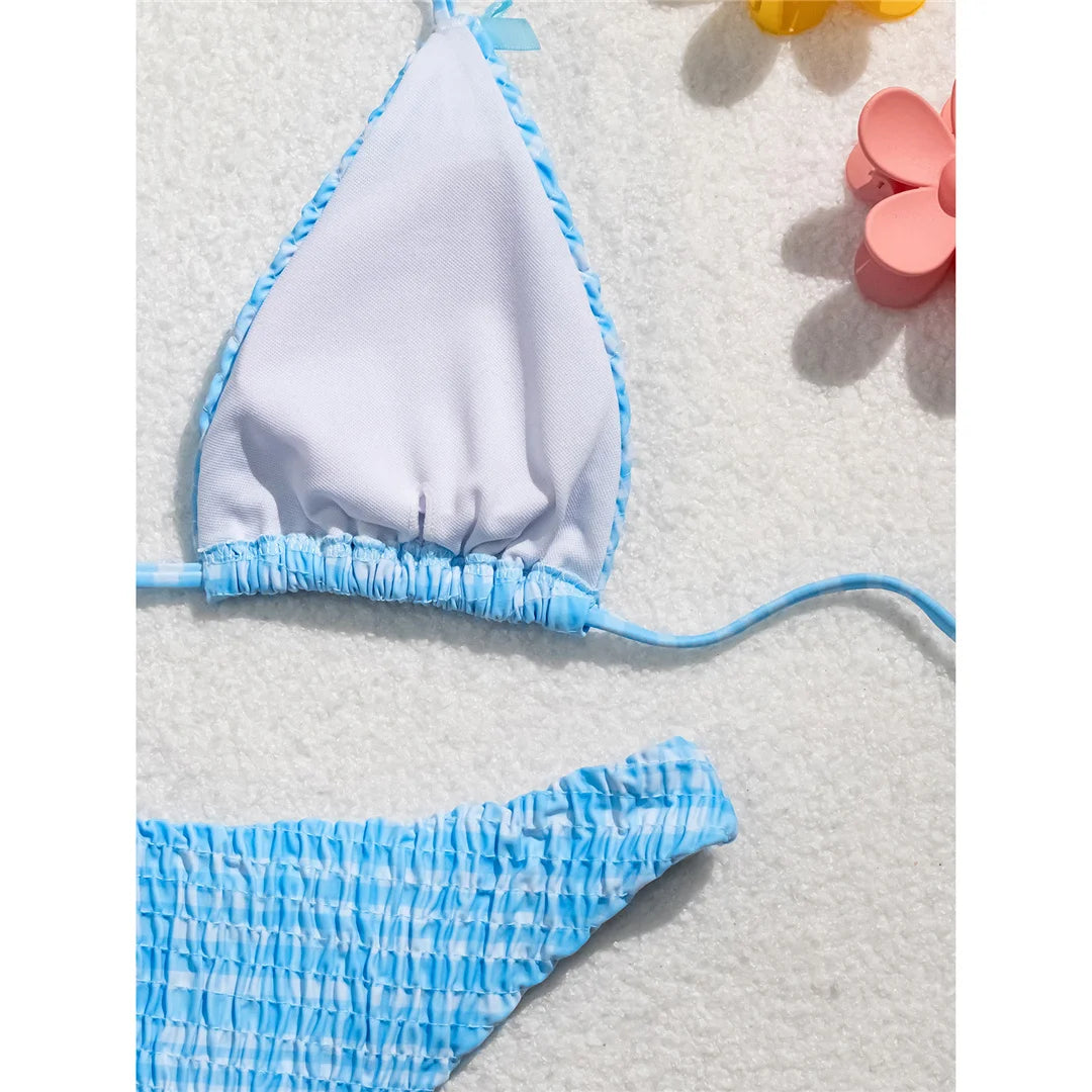 An elegant two-piece swimwear featuring a refined plaid pattern, soft wrinkled texture, and delicate bow detail, designed for a feminine and effortlessly chic beach look