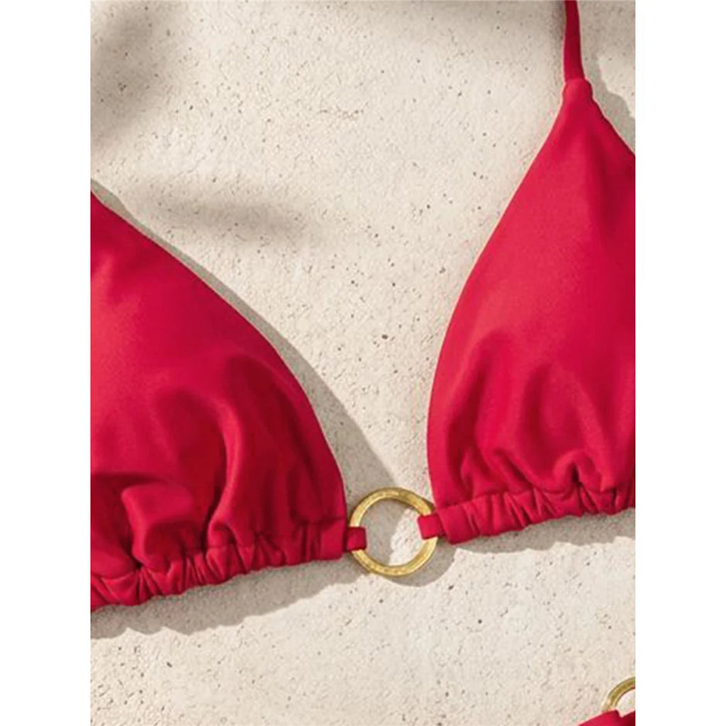 An elegant two-piece swimwear featuring a halter neckline with refined metal ring accents and a mini thong cut, designed for a bold, feminine, and confident beach look