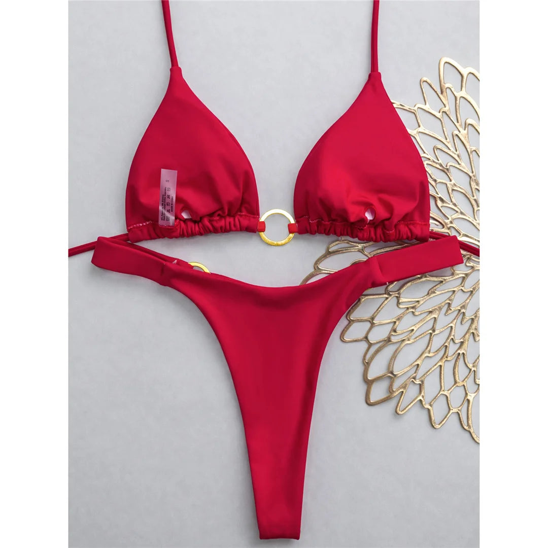 An elegant two-piece swimwear featuring a halter neckline with refined metal ring accents and a mini thong cut, designed for a bold, feminine, and confident beach look
