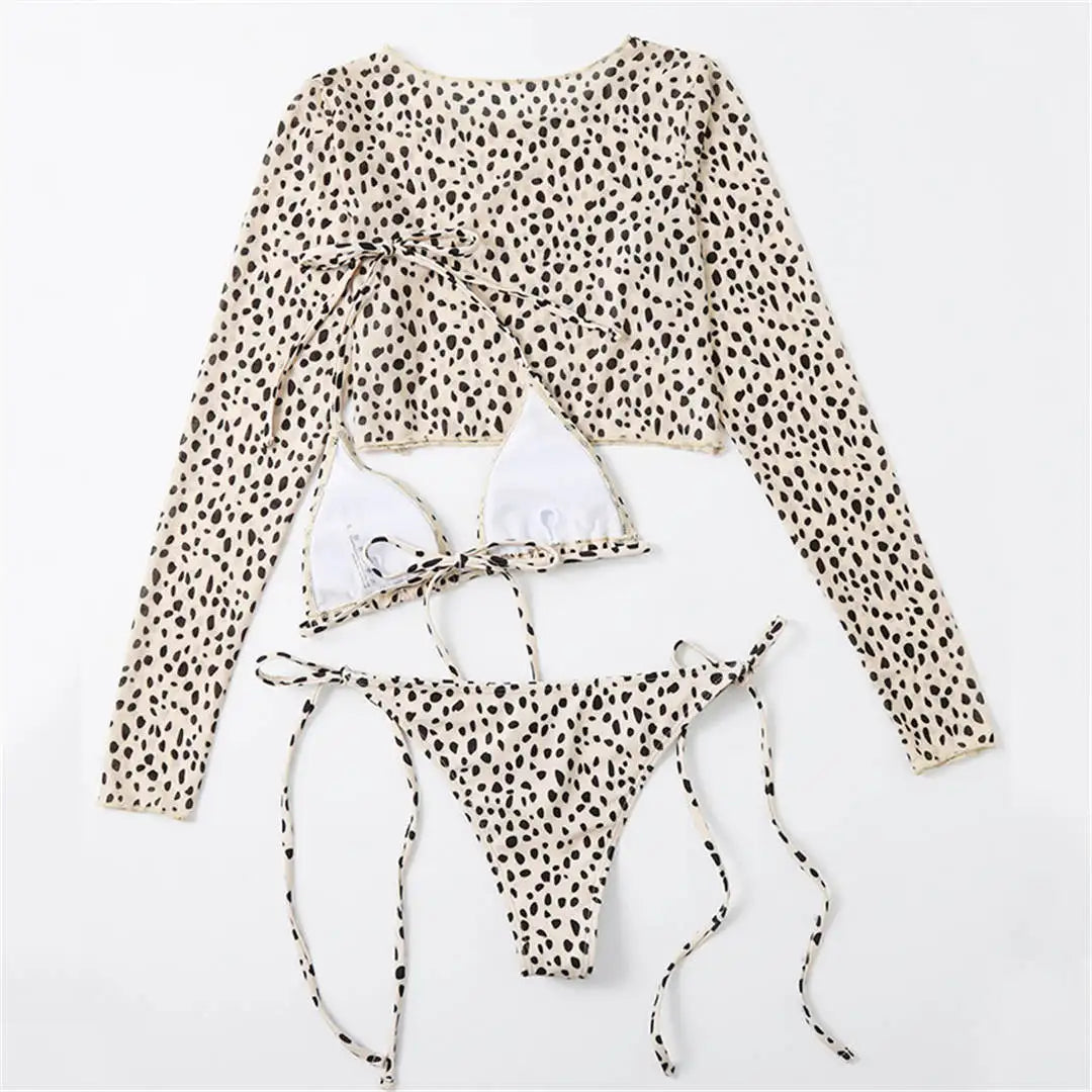 An elegant three-piece swimwear featuring a bold leopard print, long-sleeve top, and matching bikini set, designed for a feminine yet confident and stylish beach look