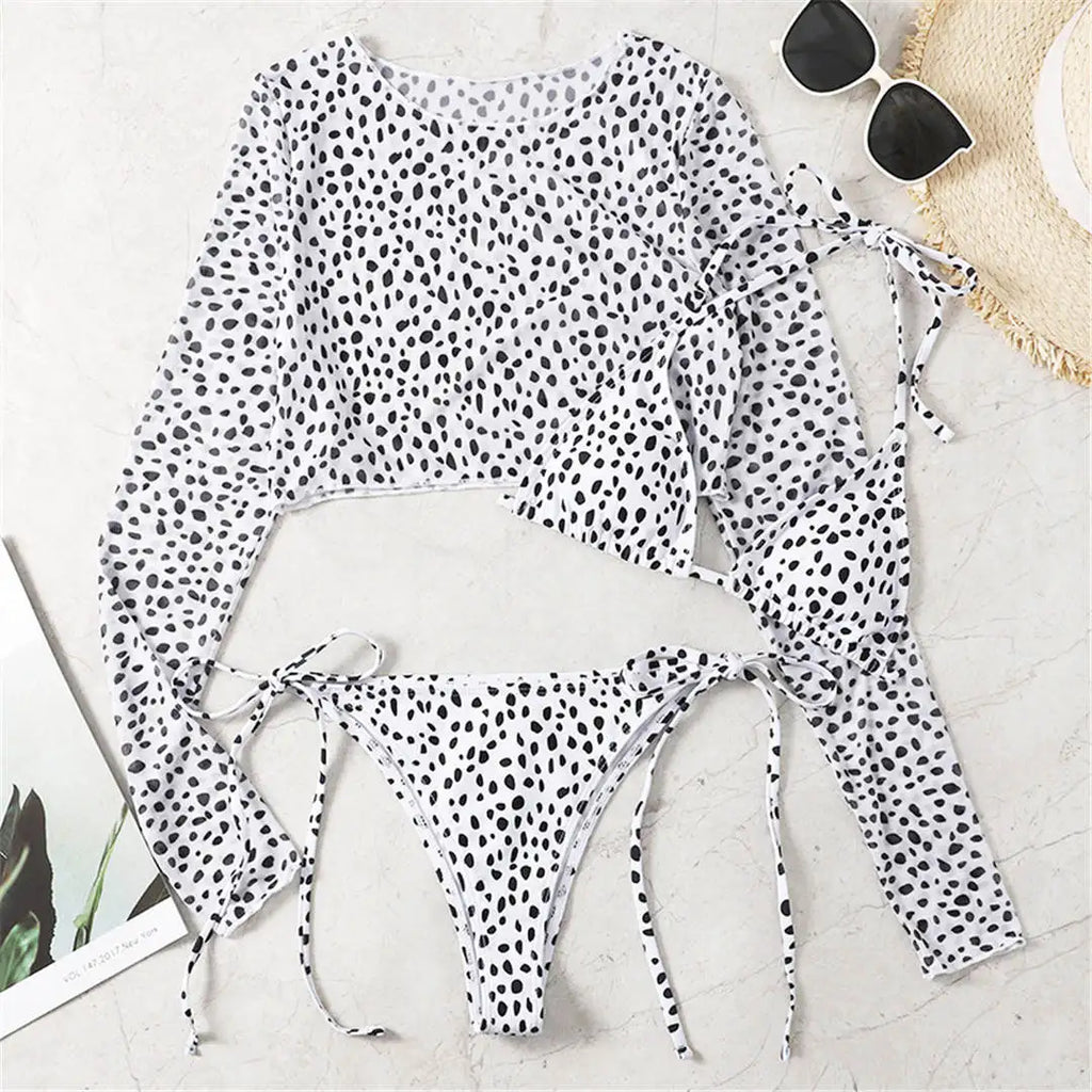 An elegant three-piece swimwear featuring a bold leopard print, long-sleeve top, and matching bikini set, designed for a feminine yet confident and stylish beach look