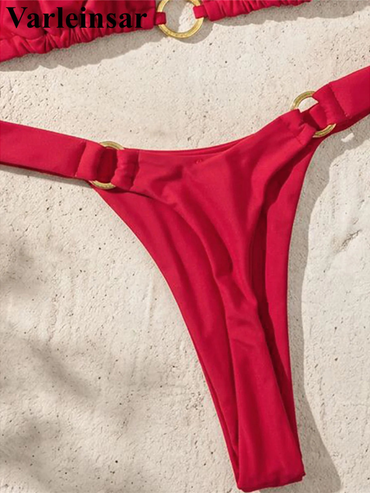 An elegant two-piece swimwear featuring a halter neckline with refined metal ring accents and a mini thong cut, designed for a bold, feminine, and confident beach look